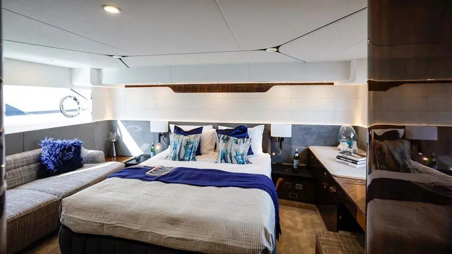 Luxurious yacht interior featuring a bedroom with a double bed, sofa, decorative cushions, and ambient lighting.